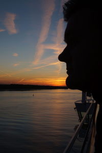 Silhouette man in sea against sky during sunset