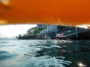 People swimming in sea against orange sky