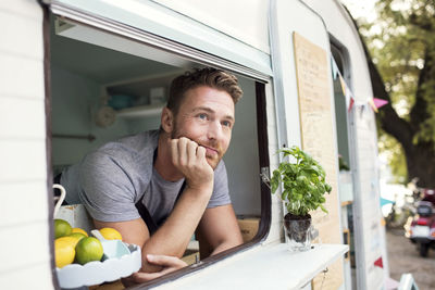 Thoughtful male owner looking out through food truck window