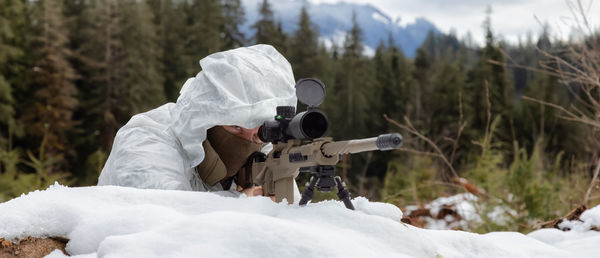 Rear view of man holding snow on field