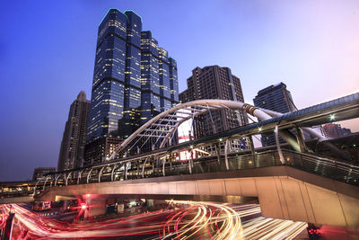 Low angle view of illuminated bridge and buildings against sky at night