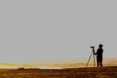 Man photographing on sea against clear sky