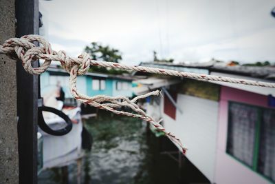 Close-up of rope tied up against houses