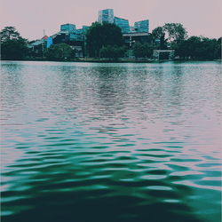 Surface level of lake by buildings against sky