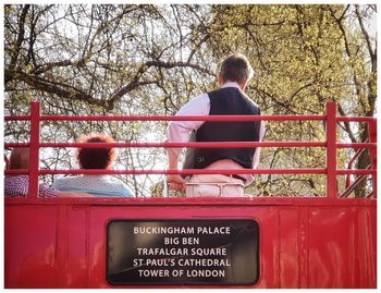 Rear view of man sitting by railing