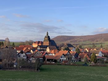 Houses in town by buildings in city against sky 