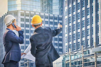 Male architects standing against modern buildings in city