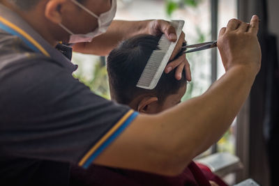 Midsection of barber cutting boy hair