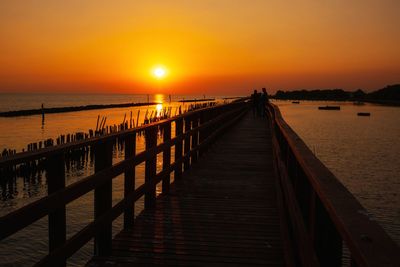Pier over sea against sky during sunset