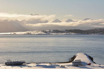 Scenic view of sea by snowcapped mountains against sky