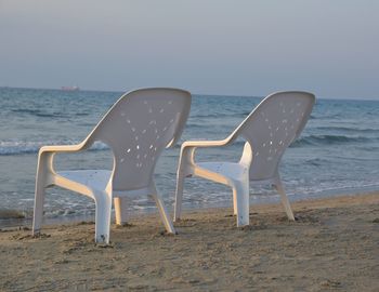 Chairs on beach against clear sky