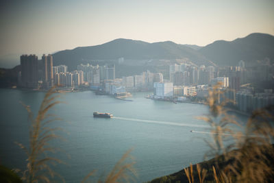 Boats in sea by city against clear sky