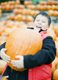 Laughing boy carrying pumpkin, new jersey, usa