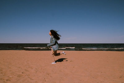 Girl on beach against clear sky