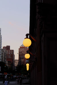 Low angle view of illuminated street light against buildings in city