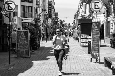 Man walking on footpath amidst buildings in city