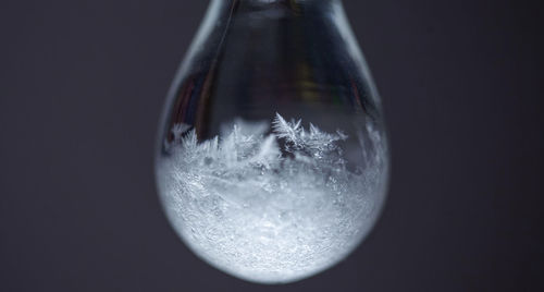 Macro shot of snowflakes reflection on drop against gray background