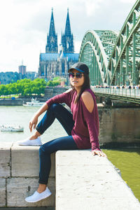 Portrait of young woman sitting on railing