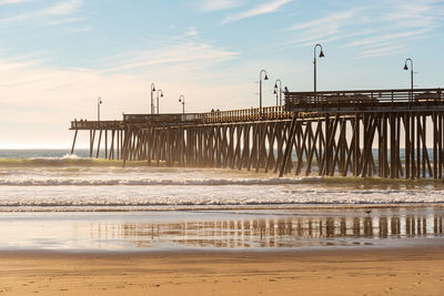 Pier on beach against sky