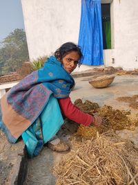 Full length of woman collecting cow dung outdoors