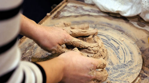 Midsection of person kneading mud