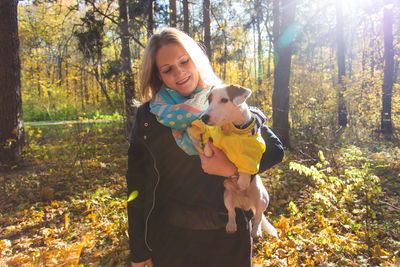 Portrait of smiling young woman in forest during autumn