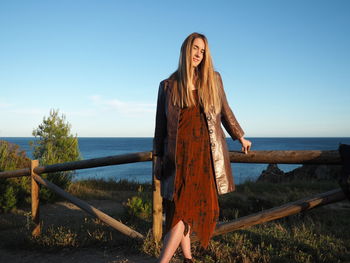 Woman standing by sea against sky