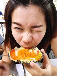 Close-up of woman winking while eating crab from shell at restaurant