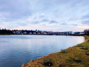 Scenic view of river by city against sky
