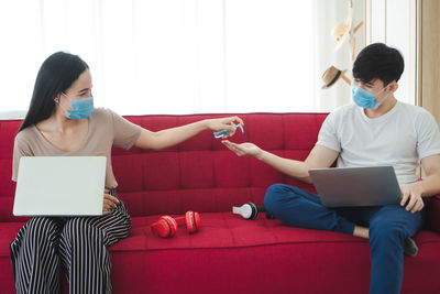 Young woman using mobile phone while sitting on sofa