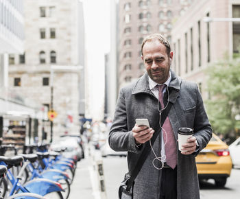 Usa, new york city, businessman on the move in manhattan looking on cell phone