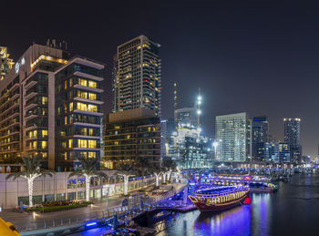 Illuminated buildings by river at night