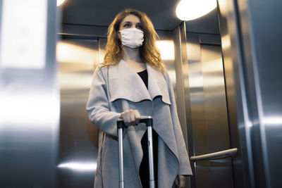 Woman holding umbrella while standing in bus