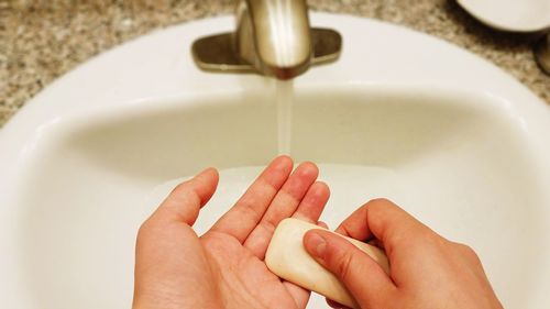 Cropped image of person washing hands at sink