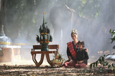 Portrait of smiling woman and girl sitting by decoration