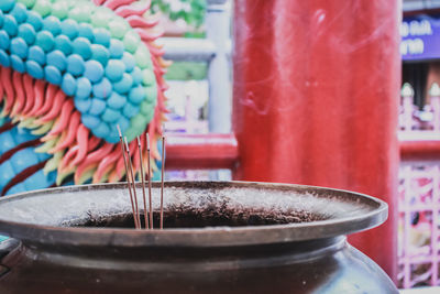 Close-up of lit incense sticks in container at temple