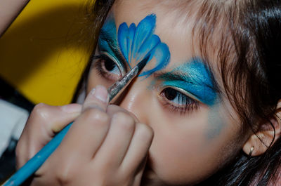 Close-up of girl getting her face paint by woman