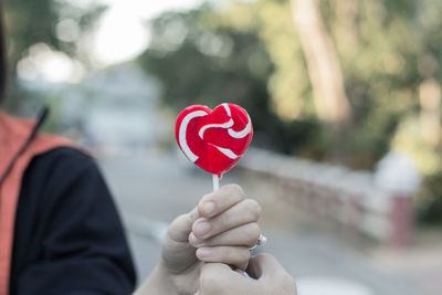 Midsection of person holding heart shape lollipop