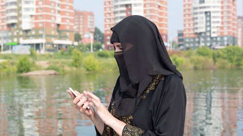 A muslim woman national clothes with her  in her hand against the background of a large city.