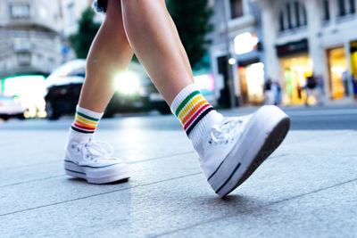 Woman's legs walking down the street with a car in the background