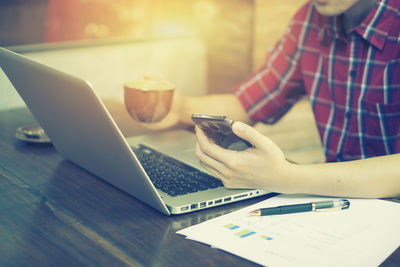 Close-up of woman using laptop on table