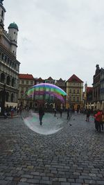 People on street amidst buildings in city against sky