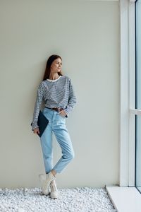 Portrait of young woman standing against wall