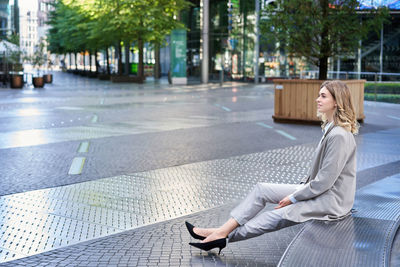 Side view of woman sitting on street