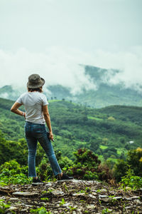 Rear view of woman standing on field against sky