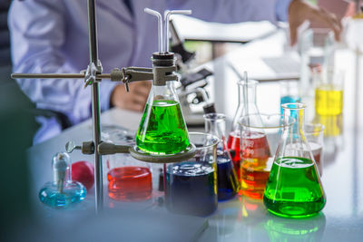 Multi colored chemicals in flasks on table in laboratory
