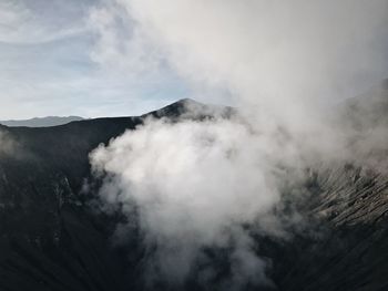 Smoke emitting from mountain against sky