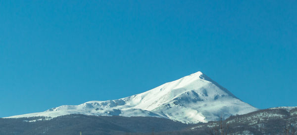 Scenic view of snowcapped mountains against clear blue sky