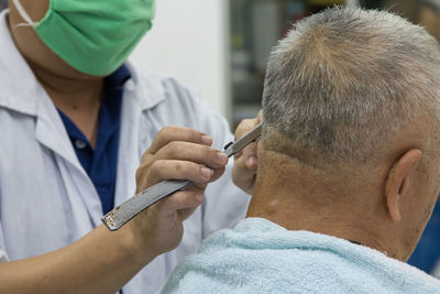 Barber cutting man hair in salon