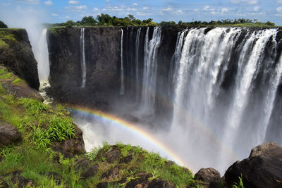 Scenic view of waterfalls at victoria falls with rainbow in the canyon